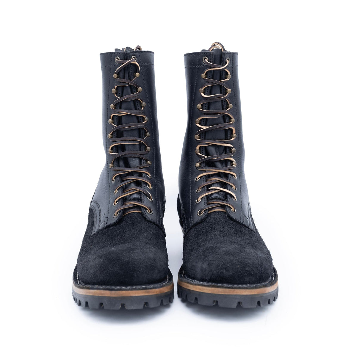 Pair of black suede boots with brown laces on a white background