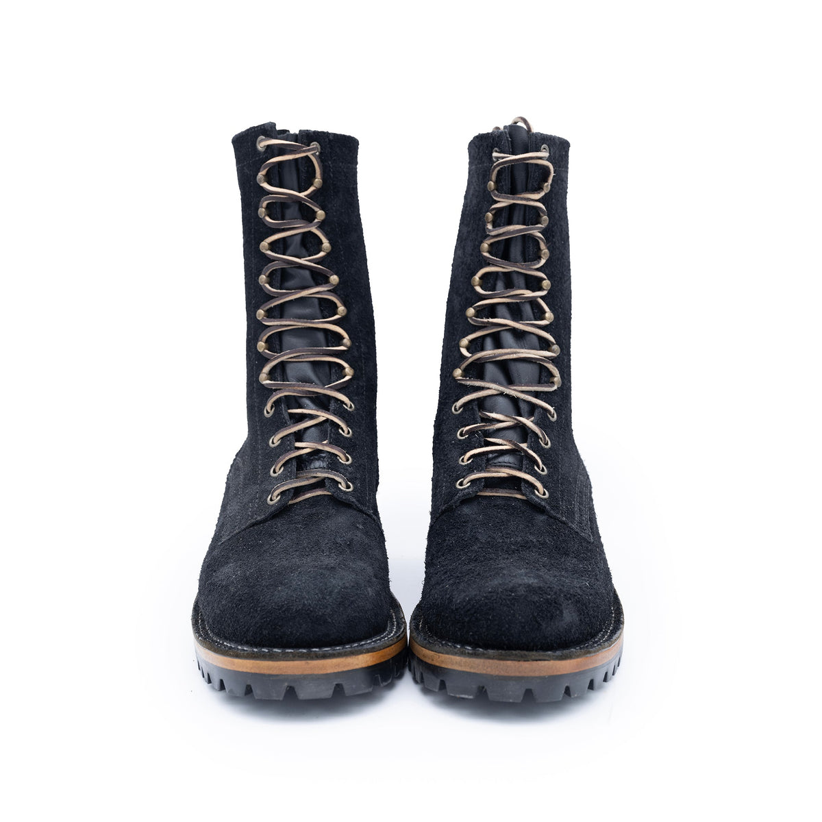 Pair of black suede boots with brown laces on a white background